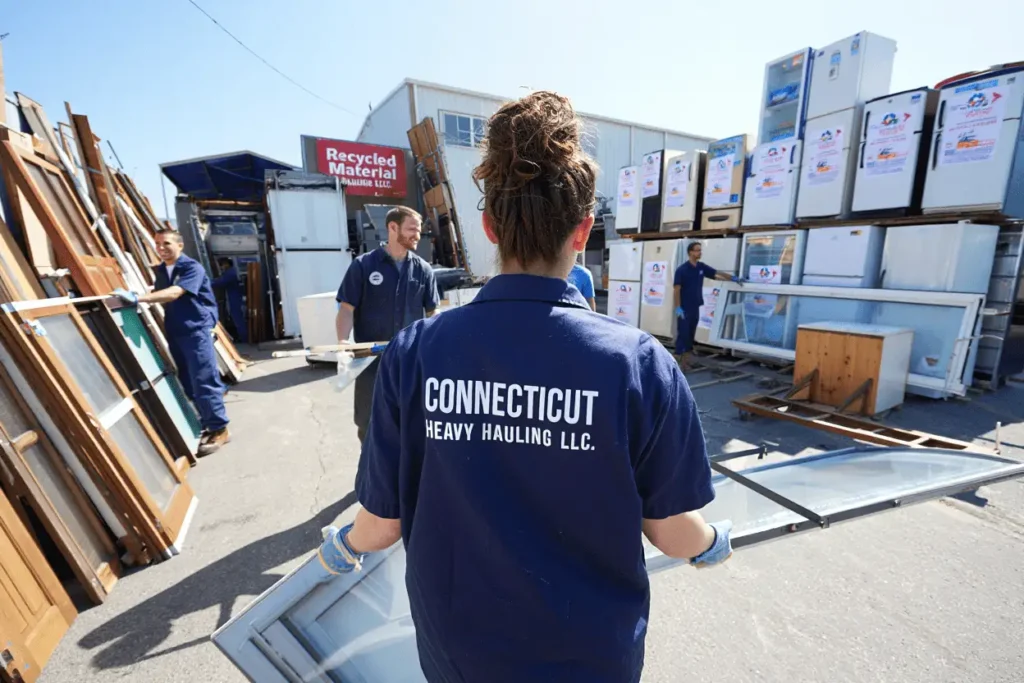 Trained junk removal worker sorting recyclable materials at certified facility in Connecticut